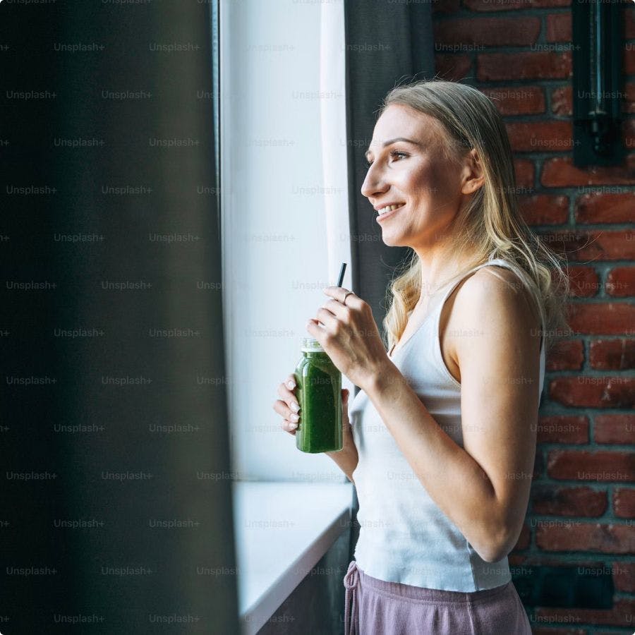 Frau trinkt einen grünen Smoothie mit Algomed Chlorella Pulver.